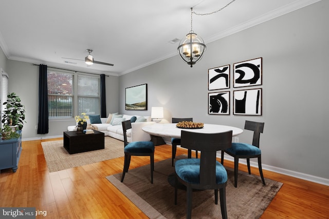 dining space with hardwood / wood-style floors, ceiling fan with notable chandelier, and ornamental molding