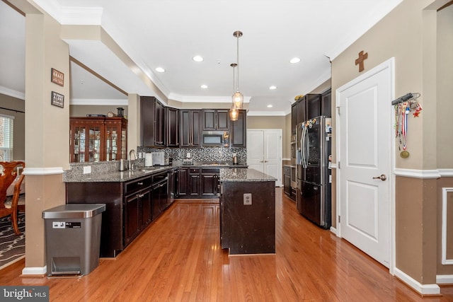 kitchen with dark stone countertops, light hardwood / wood-style floors, decorative light fixtures, a kitchen island, and appliances with stainless steel finishes