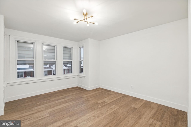 spare room featuring wood-type flooring and a notable chandelier