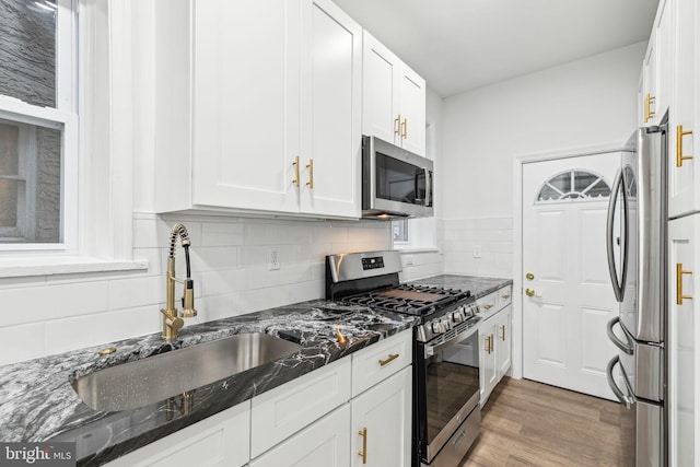 kitchen featuring dark stone countertops, white cabinets, dark hardwood / wood-style floors, and appliances with stainless steel finishes