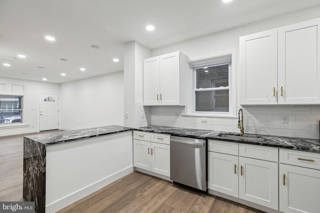 kitchen with sink, dark wood-type flooring, stainless steel dishwasher, kitchen peninsula, and white cabinets