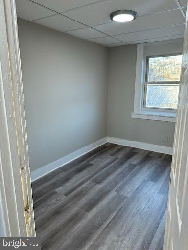 unfurnished room with dark hardwood / wood-style flooring and a paneled ceiling