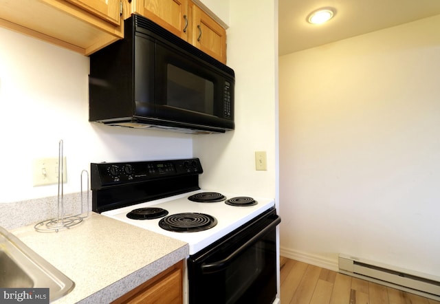 kitchen with black appliances, baseboard heating, and light wood-type flooring