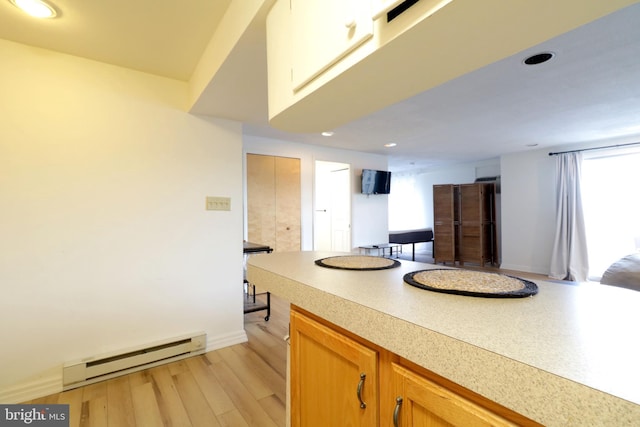 kitchen with a baseboard heating unit and light hardwood / wood-style floors