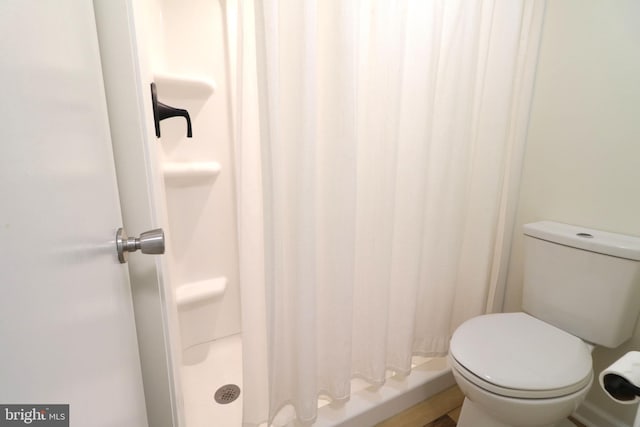 bathroom featuring toilet and a shower with curtain