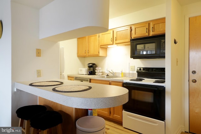 kitchen with light hardwood / wood-style floors, black appliances, sink, a kitchen breakfast bar, and light brown cabinetry