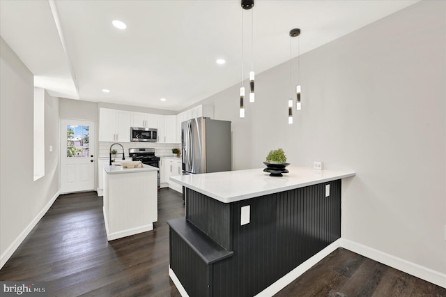 kitchen featuring white cabinets, decorative light fixtures, dark hardwood / wood-style floors, and stainless steel appliances