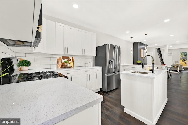 kitchen featuring pendant lighting, a kitchen island with sink, dark hardwood / wood-style floors, stainless steel fridge, and white cabinetry