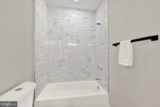 bathroom with tiled shower / bath combo and toilet