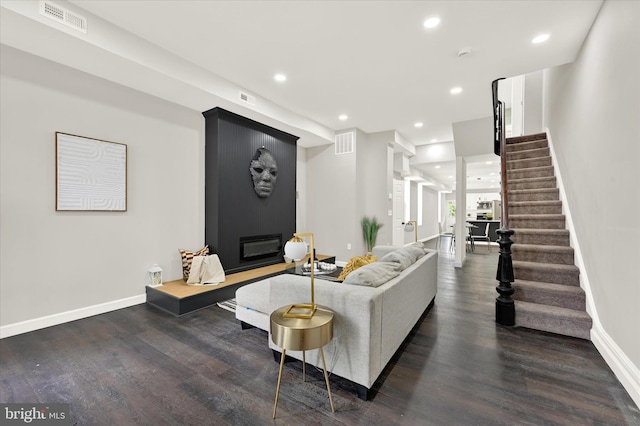 living room featuring a large fireplace and dark hardwood / wood-style flooring