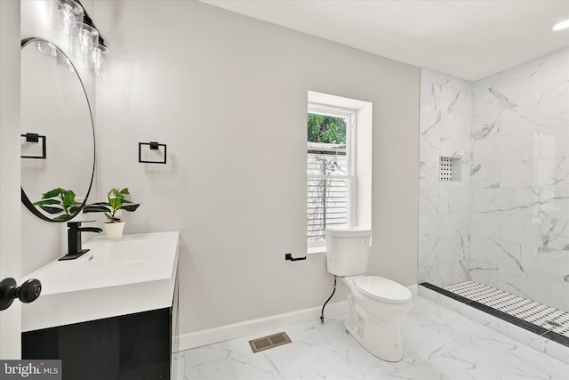 bathroom with a tile shower, vanity, and toilet