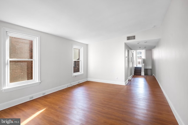 empty room with hardwood / wood-style flooring and vaulted ceiling