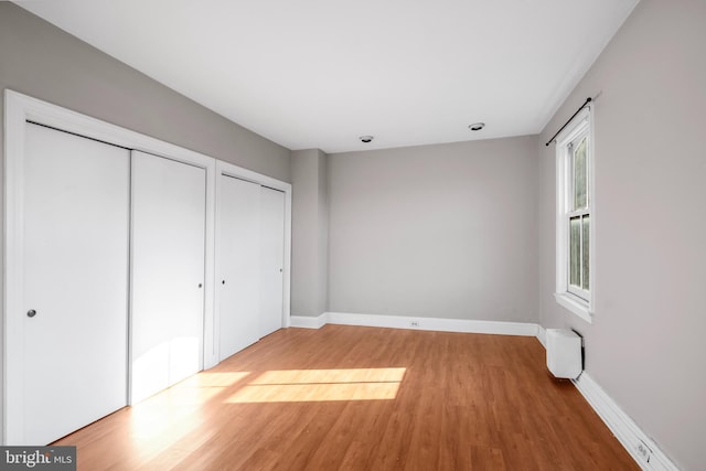 unfurnished bedroom featuring hardwood / wood-style floors and multiple closets