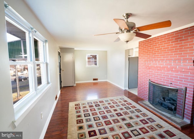 unfurnished living room featuring a fireplace, ceiling fan, and dark wood-type flooring