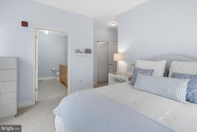 bedroom featuring connected bathroom and light colored carpet