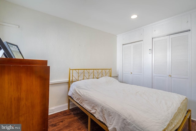 bedroom featuring dark hardwood / wood-style floors and multiple closets