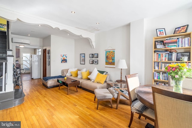 living room with an AC wall unit and light wood-type flooring