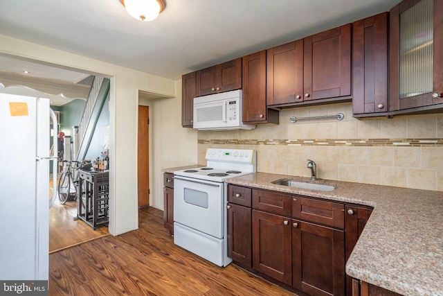 kitchen featuring tasteful backsplash, white appliances, dark brown cabinetry, dark wood-type flooring, and sink