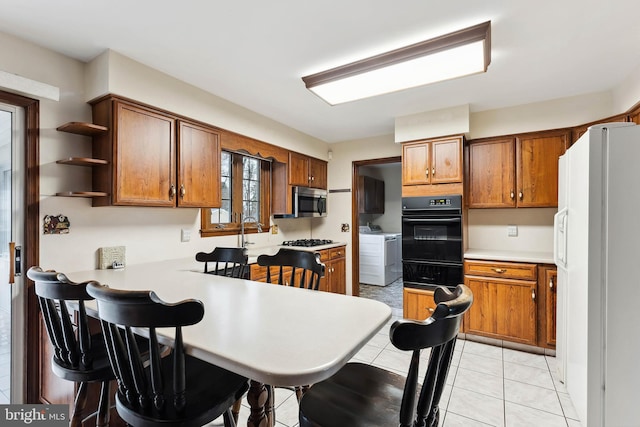 kitchen featuring white fridge with ice dispenser, independent washer and dryer, kitchen peninsula, oven, and light tile patterned floors