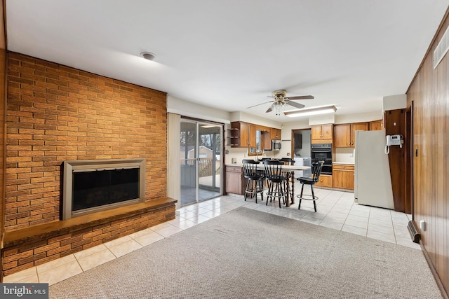 living room with wood walls, ceiling fan, light tile patterned flooring, and a fireplace