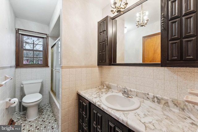 full bathroom with combined bath / shower with glass door, tile patterned floors, vanity, tile walls, and toilet