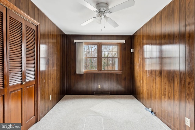 spare room with ceiling fan, carpet, and wood walls