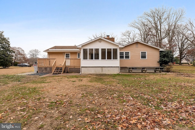 rear view of property with a yard, a deck, and a sunroom