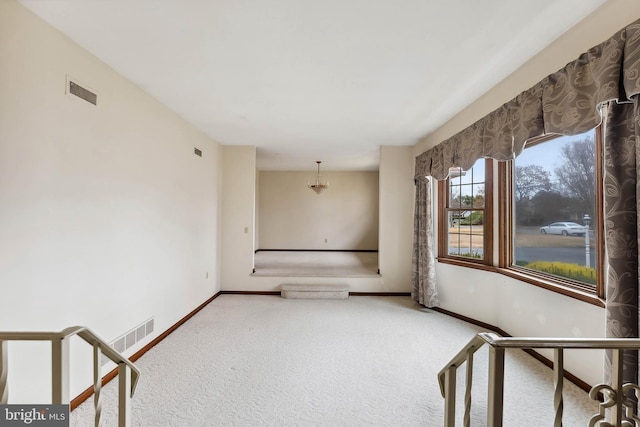 empty room featuring carpet and a notable chandelier