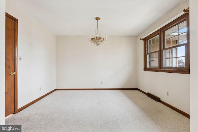 carpeted empty room with a notable chandelier