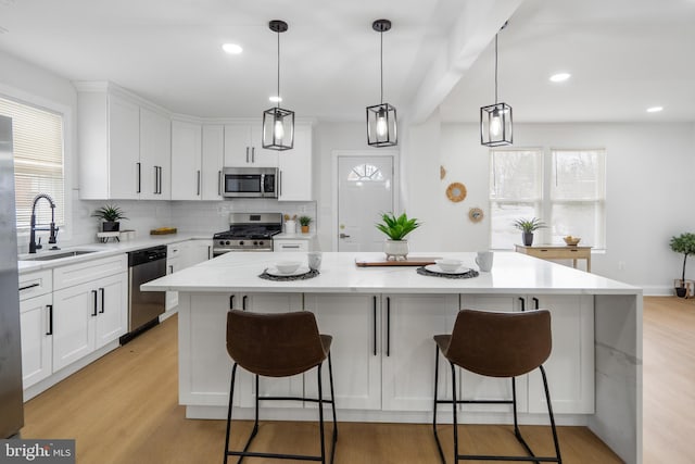 kitchen featuring white cabinets, appliances with stainless steel finishes, sink, and a center island