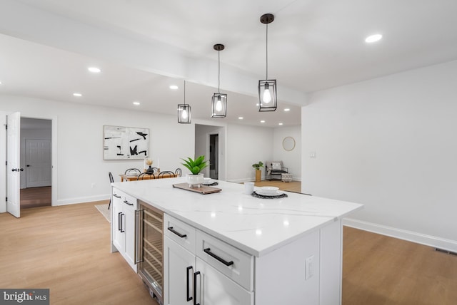 kitchen featuring light hardwood / wood-style floors, decorative light fixtures, wine cooler, white cabinets, and a center island