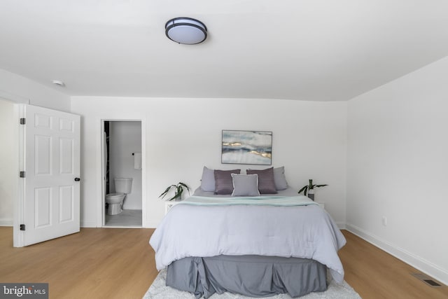 bedroom featuring ensuite bathroom and light hardwood / wood-style flooring