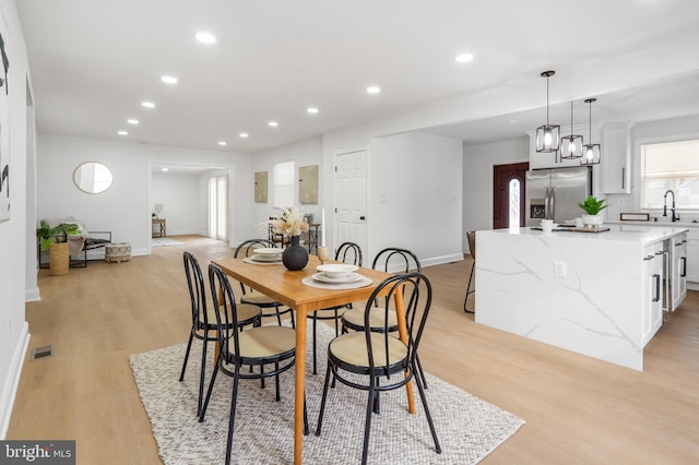 dining room featuring electric panel, light hardwood / wood-style floors, and sink