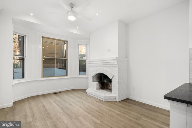 unfurnished living room featuring ceiling fan, a fireplace, and light wood-type flooring