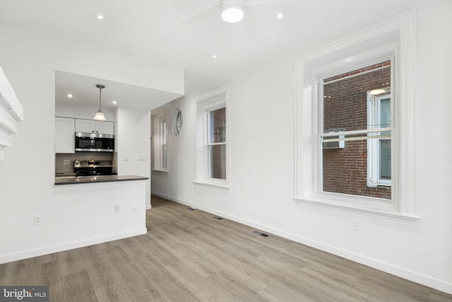 unfurnished living room featuring ceiling fan and light hardwood / wood-style floors