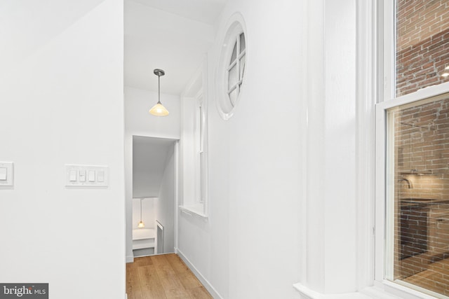 hall featuring light hardwood / wood-style flooring and brick wall