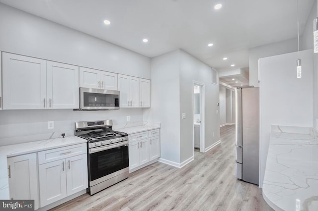 kitchen featuring white cabinets, light stone counters, light wood-type flooring, and appliances with stainless steel finishes