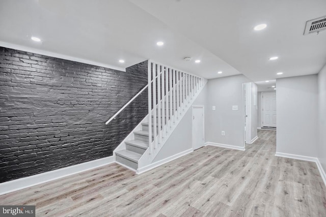 stairway with wood-type flooring and brick wall