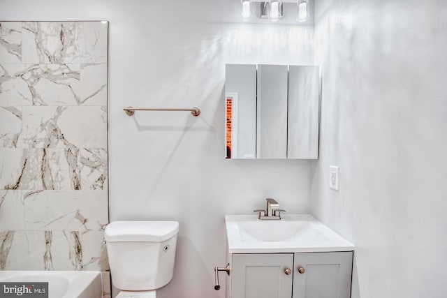 bathroom with a tub to relax in, vanity, and toilet