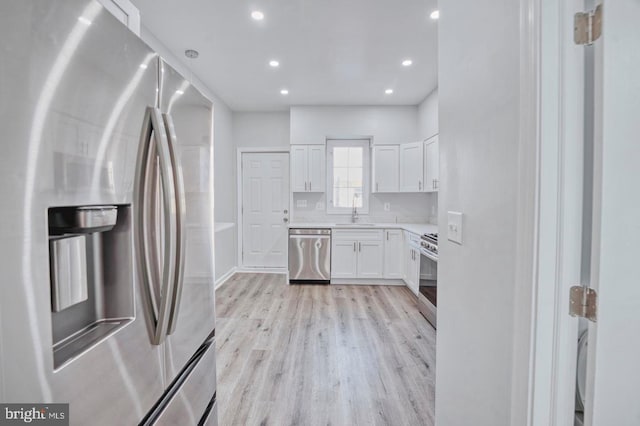 kitchen with light hardwood / wood-style floors, sink, white cabinetry, and stainless steel appliances