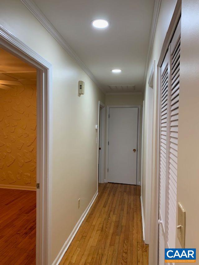 hall featuring ornamental molding and light hardwood / wood-style floors