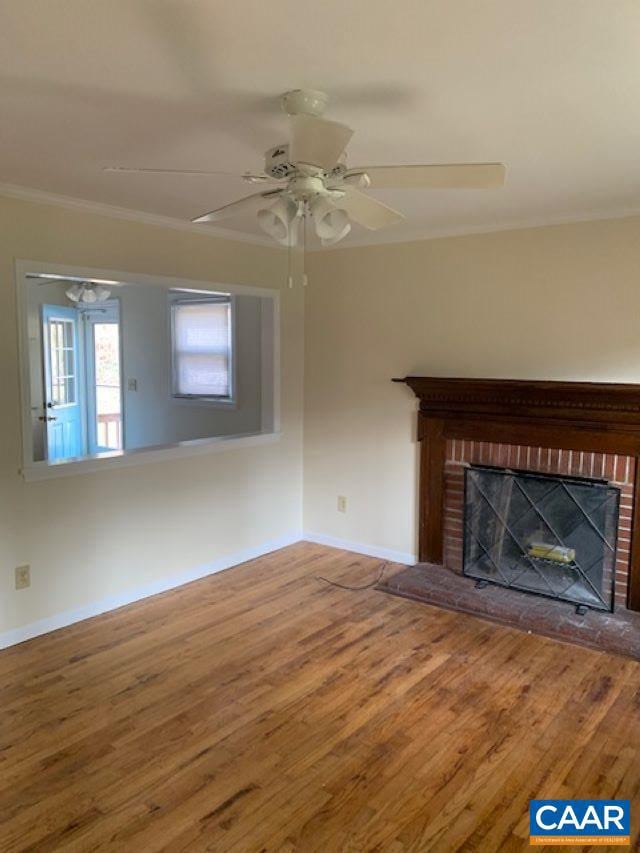 unfurnished living room with ornamental molding, a brick fireplace, and hardwood / wood-style floors