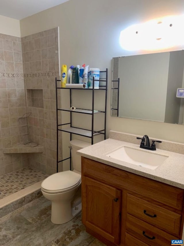 bathroom with vanity, toilet, and a tile shower