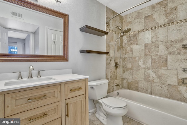 full bathroom featuring vanity, tiled shower / bath, and toilet