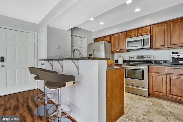 kitchen featuring appliances with stainless steel finishes, a breakfast bar area, and dark stone countertops