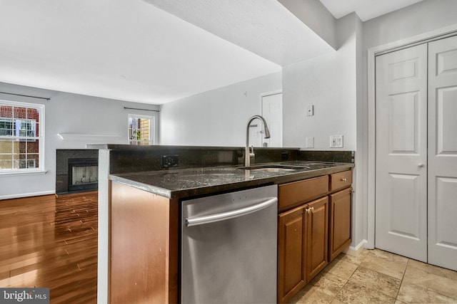 kitchen with dark stone countertops, sink, stainless steel dishwasher, and kitchen peninsula