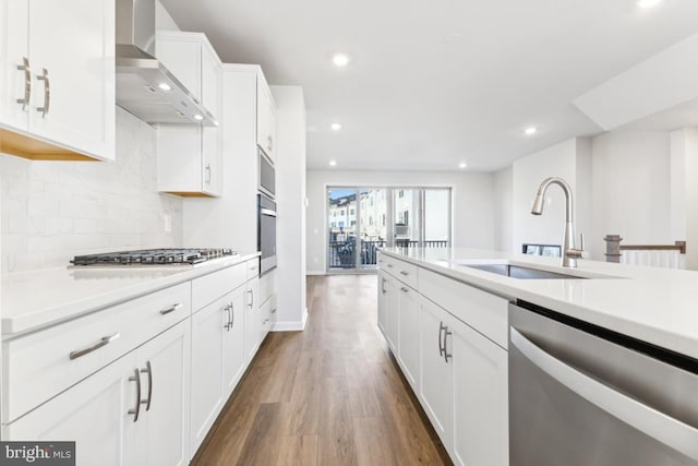 kitchen featuring white cabinetry, sink, wall chimney range hood, dark hardwood / wood-style flooring, and appliances with stainless steel finishes