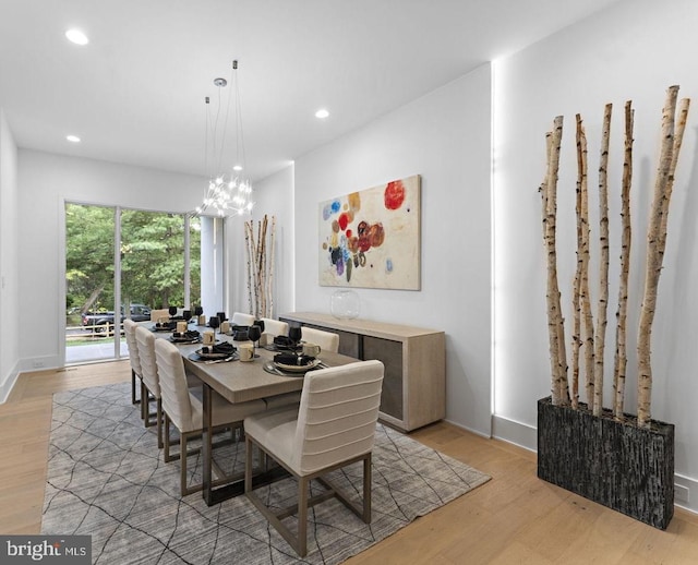 dining space featuring light wood-type flooring and an inviting chandelier