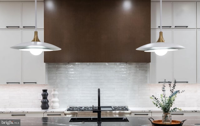 kitchen featuring tasteful backsplash, light stone counters, and sink