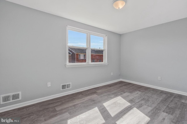 unfurnished room with visible vents, baseboards, and wood finished floors